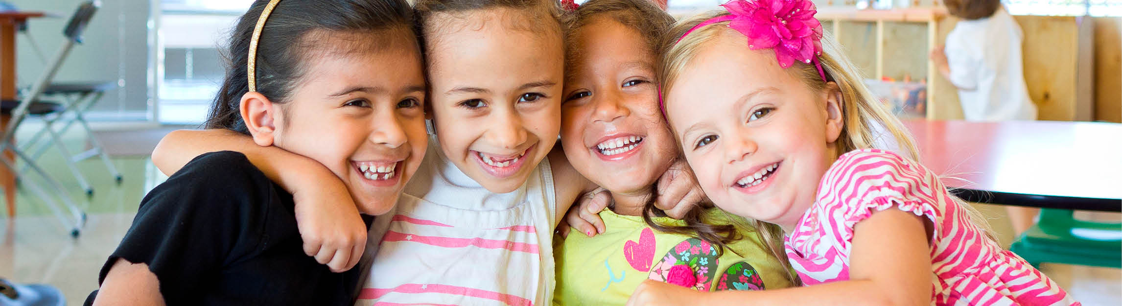 Four girls hugging and smiling in Child Watch