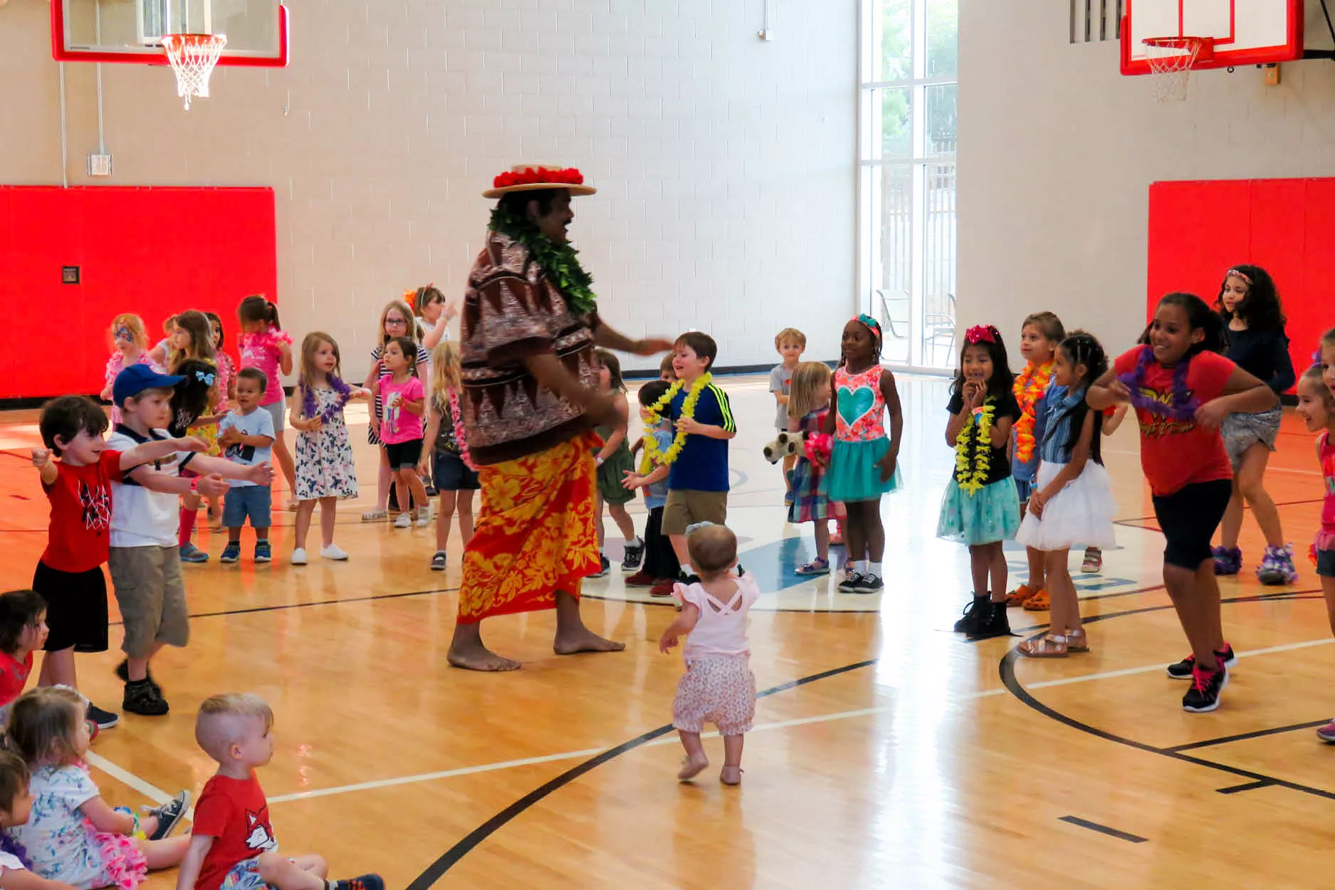 Man in Hawaiian clothing speaking to large group of children