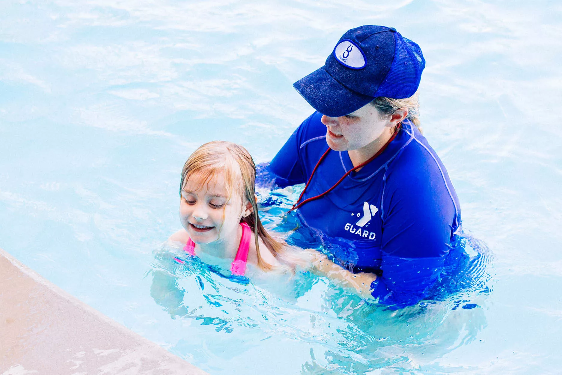 Lifeguard assisting female child during a swim lesson
