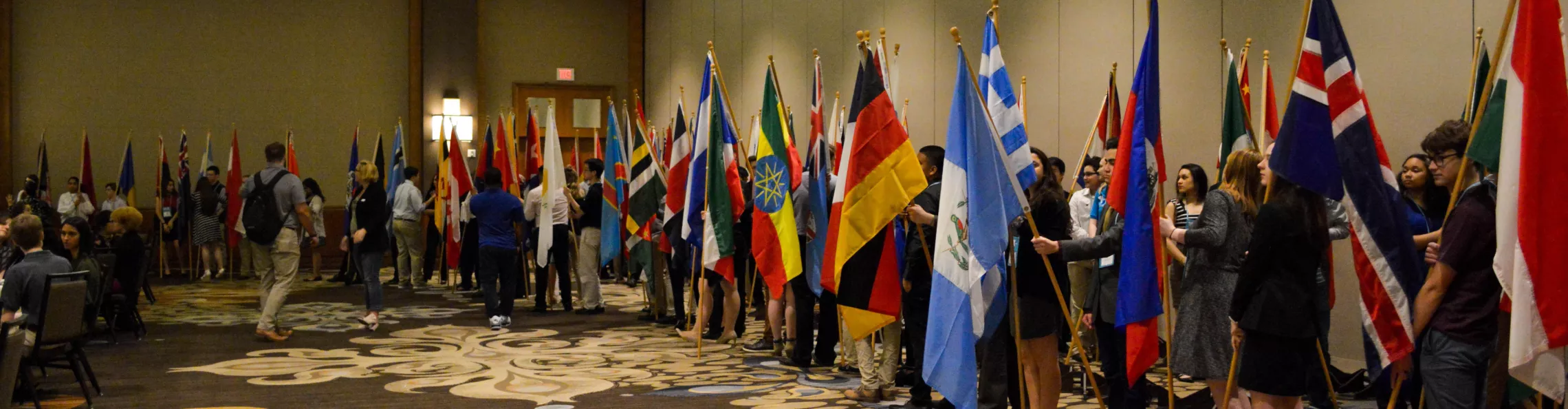 Long line of teens holding flags from around the world