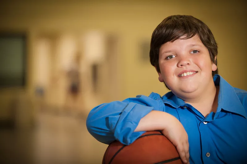 young boy smiling holding a basketball
