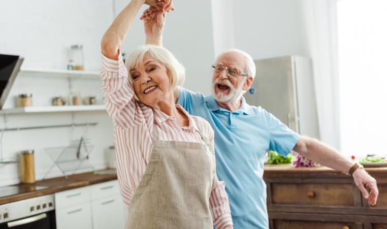 Smiling senior couple dancing in kitchen