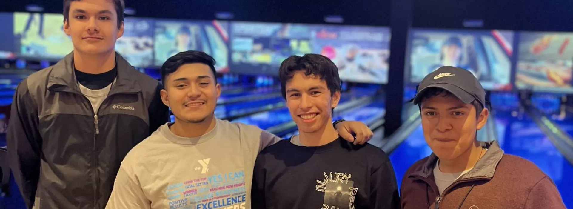 4 male students posing in front of bowling alley